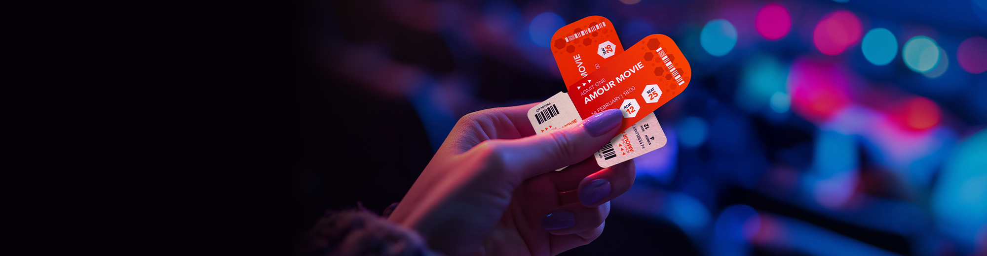 A hand holding two red movie tickets in a heart shape.