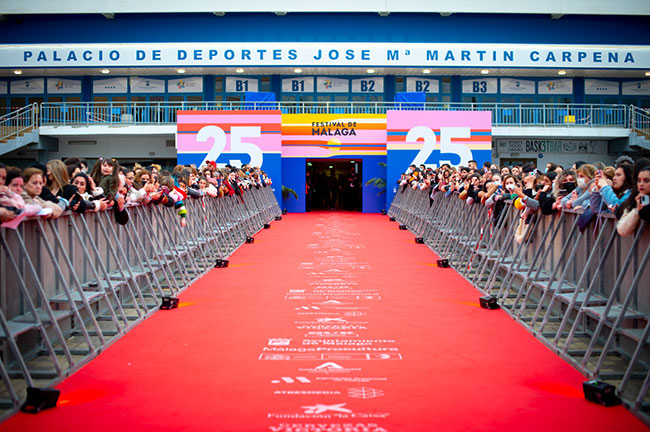 A long red carpet is flanked by onlookers on both sides.