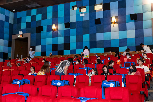People settle into their seats in a movie theatre.