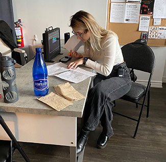 A woman sits at a table reviewing paperwork.