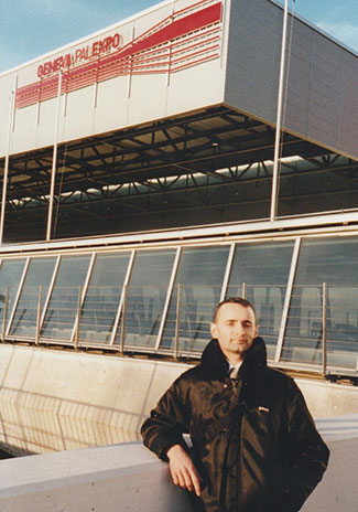 A man stands in front of a large building with the words “Geneva Palexpo” on the front.