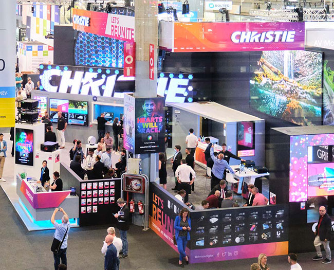 A birds eye view of the Christie tradeshow booth in the middle of a busy tradeshow floor
