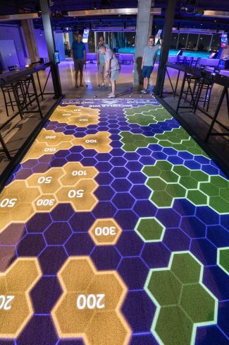 A golfer readies a shot onto a projection mapped artificial putting turf.