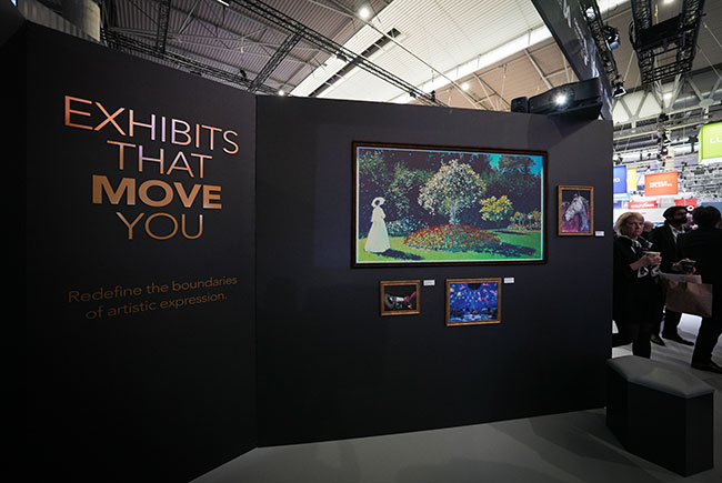 Art work is projected onto a dark wall with gold picture frames. Text reads, “Exhibits that move you”. 