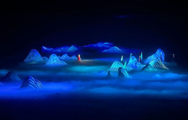 Performers on a stage with blue fog at their feet.