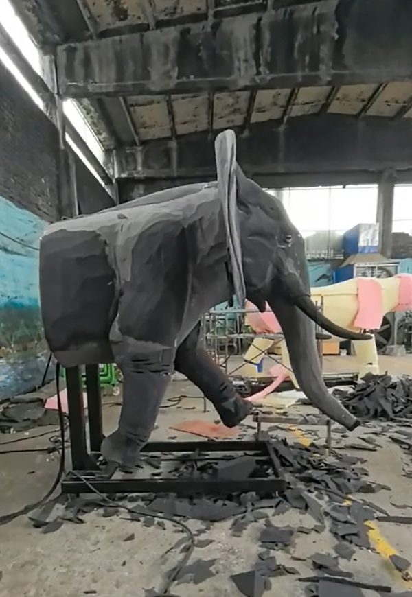 An animatronic elephant being covered in grey silicone “skin”.