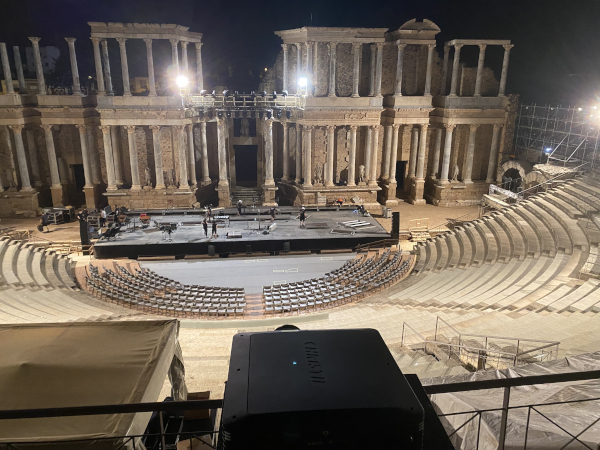 A stage is being set up in an ancient stadium with a projector in the foreground.