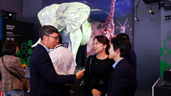 A Christie rep speaking with attendees in front of the elephant display at the Christie booth.