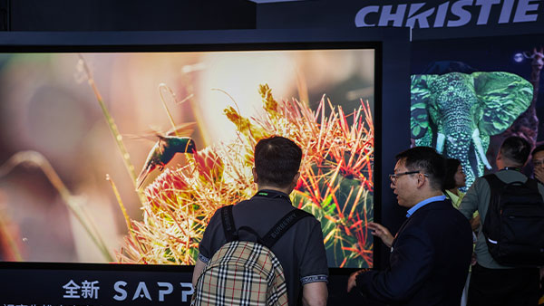 A person looking at a Christie Sapphire 4K40-RGBH display and speaking with a Christie Rep at InfoComm China 2025.